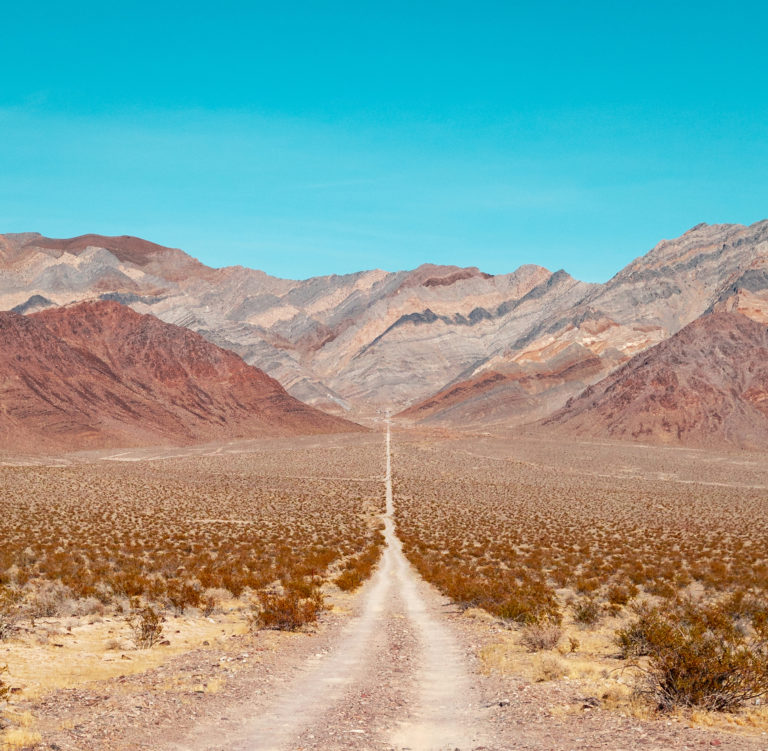 A desolate road in the Nevada Desert leading to a beautifully painted mountain scape
